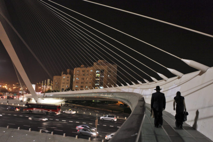 Ulrta orthodox jewish couple walks on the Harp bridge at night in Jerusalem